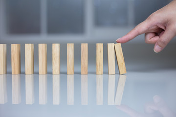 Hand pushing a dominoes concept.