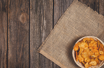 Heap of potato chips in vintage bowl on old wooden table background close-up with copy space for your text