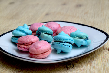Home baked pink and blue macarons on a plate, a delicious French sweet pastry