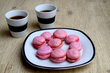 Cup of coffee and pink macarons on the table