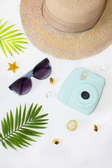 Flat lay summer beach holiday accesorries on white background with palm leaf, camera, straw hatand and sunglasses. Space for text. Travel and beach vacation, top view. Fashionable sunglasses. Minimal.