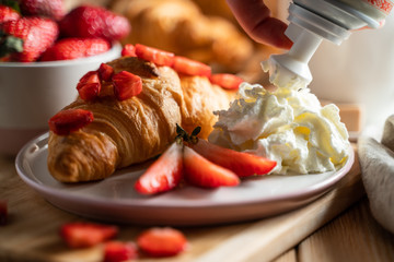 Croissant with cream cheese, strawberries for breakfast