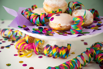 Traditionelle Deutsche Berliner Pfannkuchen Krapfen zu Fasching, Karneval oder Silvester mit bunten Konfetti und Luftschlangen