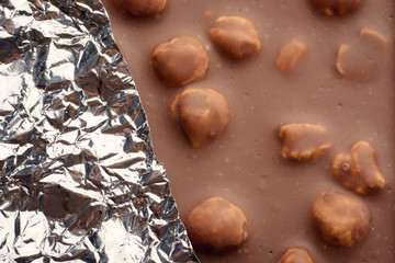 Bar of milk chocolate with nuts covered with foil.