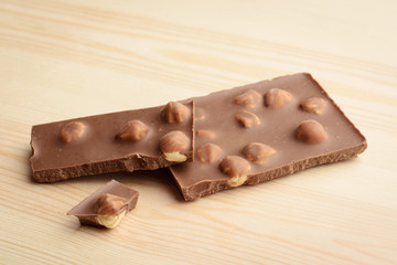 Milk chocolate with nuts on light wooden background