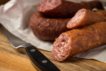 Ringwurst Salami und Bierbeißer Wurst in Wachspapier mit Messer auf Vesper Holzbrett