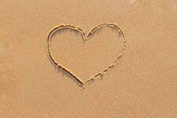 heart drawn on sand by hands
