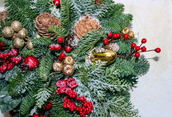 Christmas composition of pine branches, golden Christmas decorations, red berries and artificial snow.