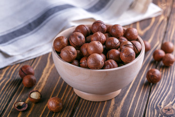 macadamia nuts in wooden bowl on wooden surface. natural healthy food.