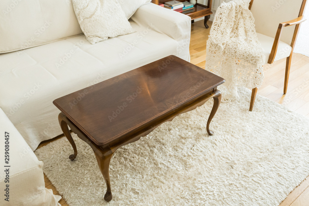 Wall mural Coffee table in the bright living room with a white sofa and vintage decor