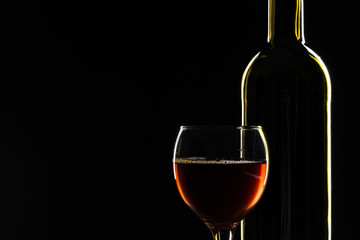  wine bottle and wine glass in a black background