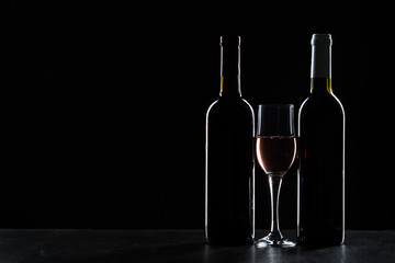 Bottles of wine and different glasses of wine on a dark background