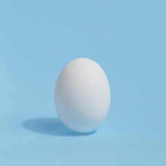 White chicken egg on a blue background. Preparation for coloring of Easter egg. Easter holiday concept.