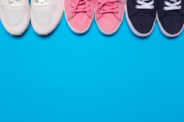 colorful  shoes top view. Set of different sneakers on blue background, copy space.