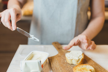 Fototapeta na wymiar Close up of senior woman hands cutting baguette - making sandwich bruschetta - home cooking
