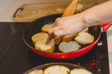 Closeup of housewife fry baguette pieces in a frying pan - making crispy sandwiches