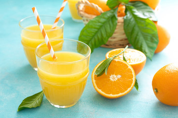 Orange freshly squeezed juice in glass and fresh fruits on a blue vivid background