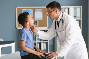 Fototapeta premium Pediatrician examining African-American boy in clinic