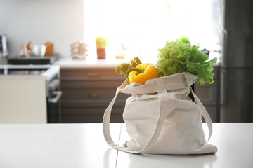 Eco bag with fresh vegetables on table in kitchen