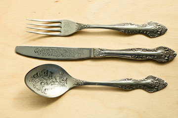 Engraved old silver cutlery. Fork, spoon and knife view from above.