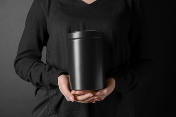 Woman with mortuary urn on dark background, closeup
