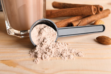 Scoop with protein powder on wooden table