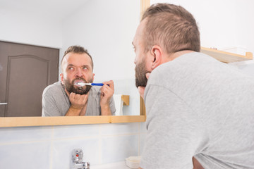 Bored guy brushing his teeth in bathroom