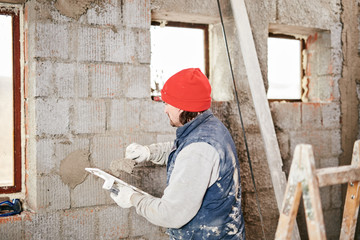 Real construction worker making a wall inside the new house.