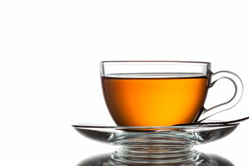 A cup of black tea and a spoon on a white table with reflection