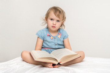 Cute little child in blue dress reading a book