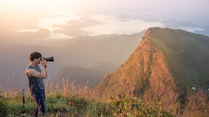 Young Asian male photographer and traveler taking photo of mountain landscape scenery during...
