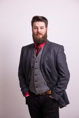 Fototapeta premium Cool young bearded man in grey business suit looking at the camera over white background