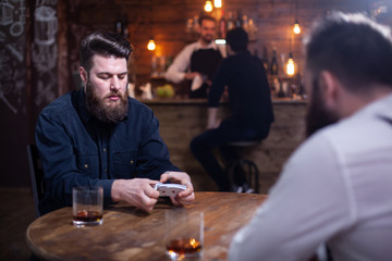 Two bearded hipsters playing a card game in a pub