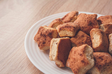 A lot of newly-baked cookies with cinnamon on white plate