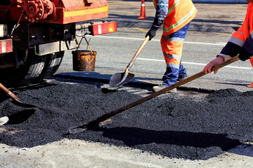 The working team renews a portion of asphalt with shovels in road construction