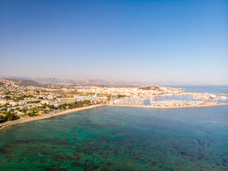 Fototapeta na wymiar marineta 04Aerial view of Denia city in Spain on a sunny day. Marineta Beach is in the foreground. Some mountains in the background