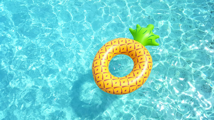 Pineapple life ring floating in crystal blue sea water on a sunny day for relaxation and happy summer holiday vacations concept.