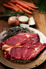 Raw Beef steak and fresh ingredients for cooking on rustic background