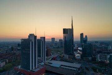 Fototapeta na wymiar Milan (Italy) city skyline at dawn, aerial view, flying over financial area skyscrapers in Porta Nuova district. Unicredit Tower office building at sunrise.