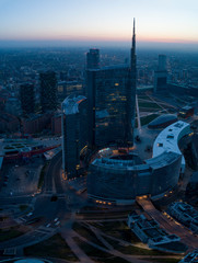 Milan (Italy) city skyline at dawn, aerial view, flying over financial area skyscrapers in Porta Nuova district. Unicredit Tower office building at sunrise.