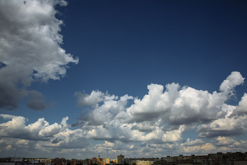 Beautiful fluffy clouds in the blue sky. City landscape. Good weather.