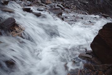 Waterfall in a high gorge among the brown rocks and fog of the Altai mountains. close up