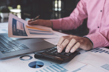 Fototapeta premium Bookkeeper accounting Concepts, Male use calculator, pen , and computer laptop to working financial and budget, inspector accountant concept.
