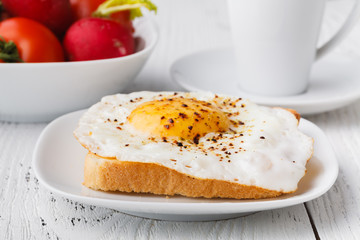 Tasty sandwich toast with avocado, tomato and poached egg on wooden chopping board