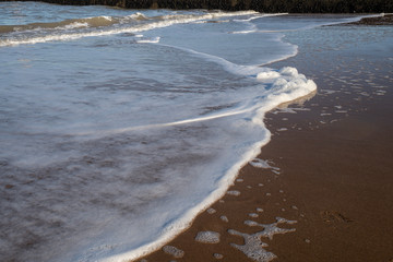 Sea foam washing up on the beach in Kent, UK