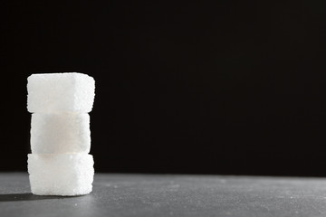 Sugar lumps piled up together against a black background