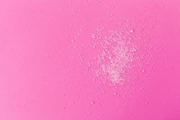 White sugar on a pink background top view