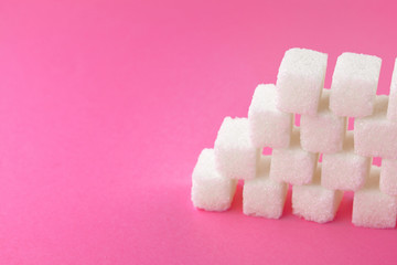 Cubes of sugar on bright pink background