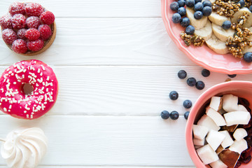 Sweet unhealthy desserts and healthy tasty snacks on white wooden table, copy space for text. 