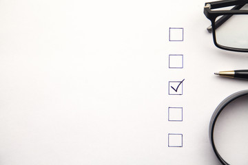 Pen, glasses, magnifying glass and Checklist on white paper. Business concept